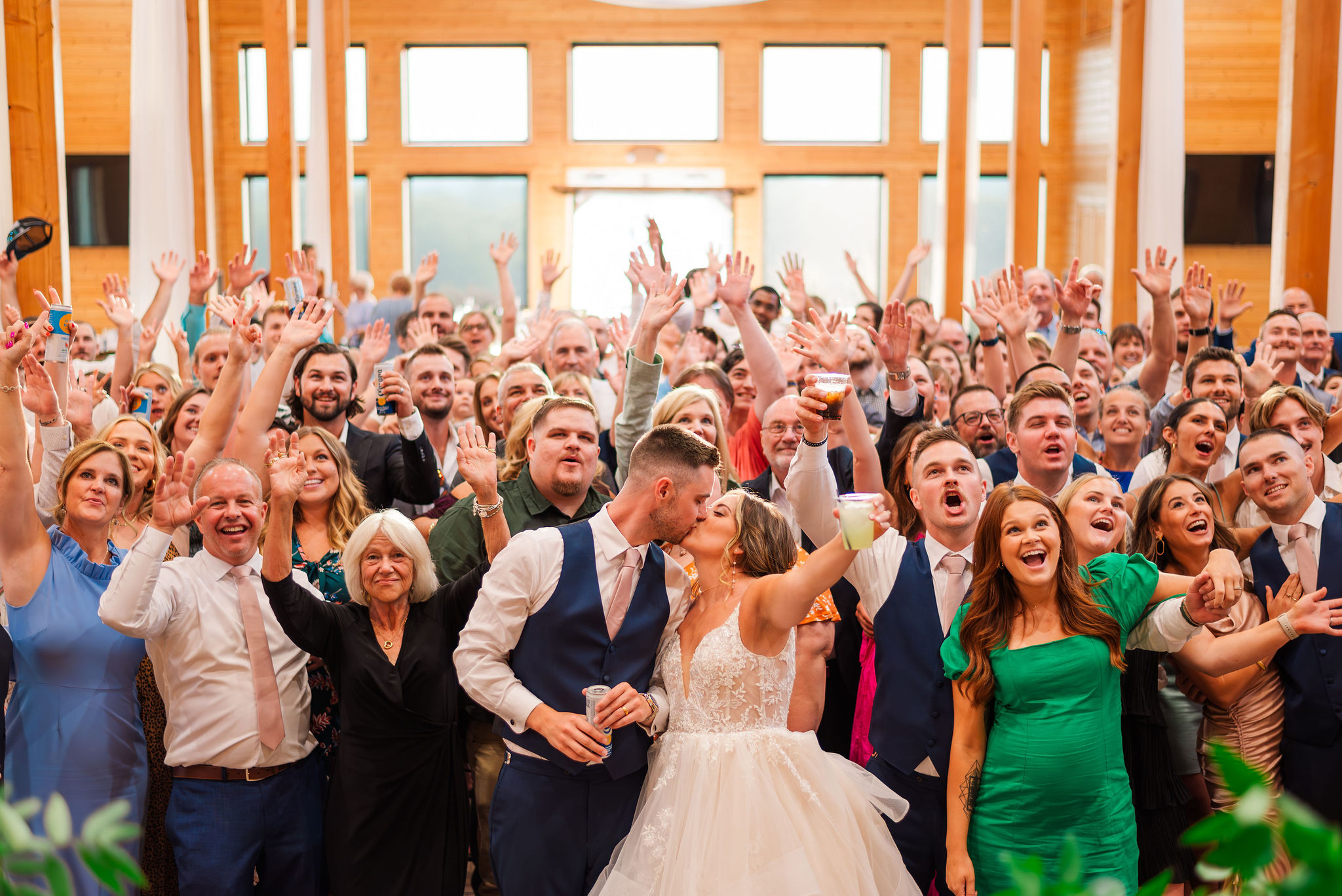 bride and groom kissing in the middle surrounded by guests to create a selfie like image